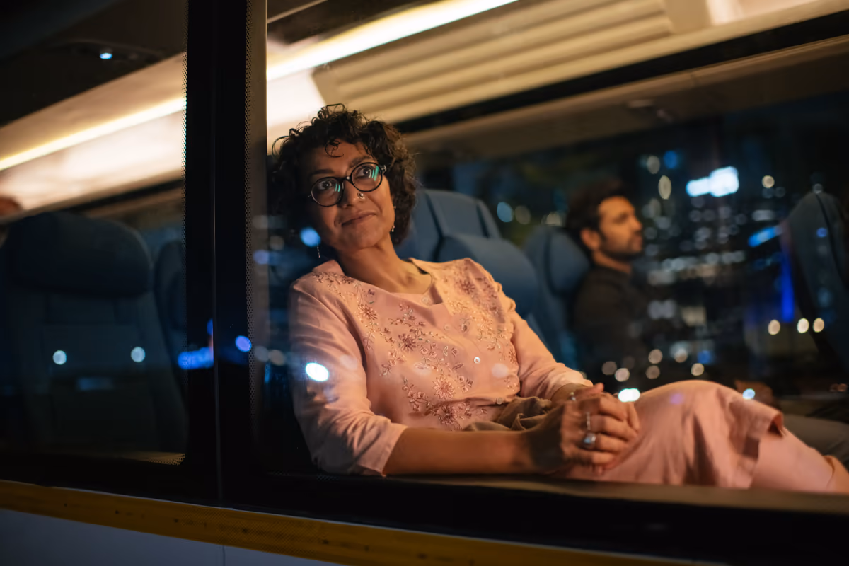 A passenger gazing out of a Cityflo bus window at the city lights