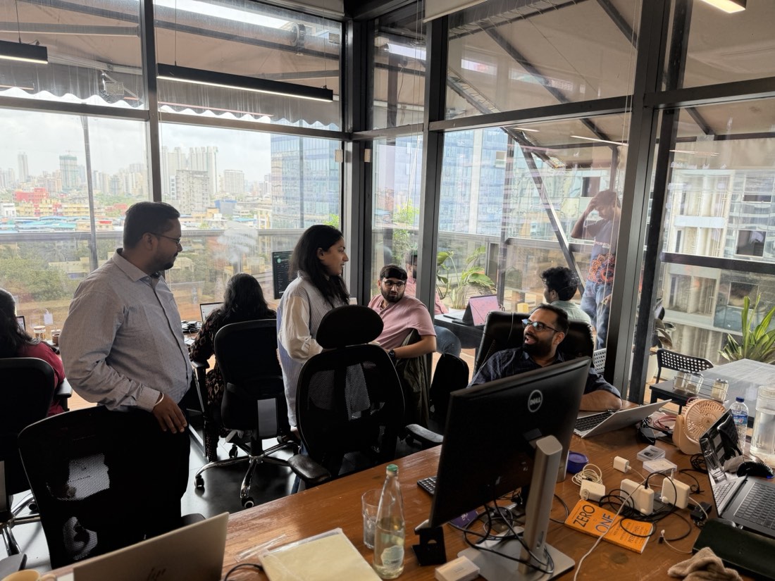 Desks by the glass wall, the Mumbai skyline behind